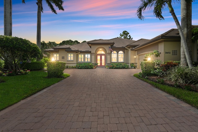 view of front of property with french doors, a garage, and a yard