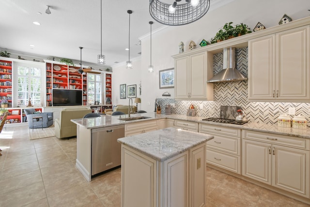 kitchen with stainless steel appliances, wall chimney exhaust hood, decorative light fixtures, and cream cabinets