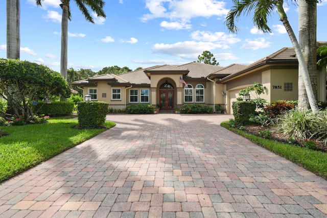 mediterranean / spanish home featuring french doors, a garage, and a front lawn