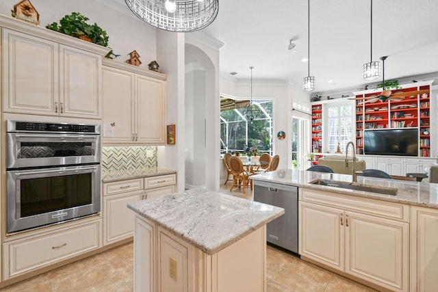 kitchen featuring cream cabinets, stainless steel appliances, a kitchen island, light stone countertops, and pendant lighting