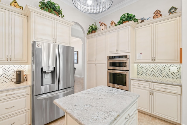 kitchen with stainless steel appliances, light stone counters, a kitchen island, and ornamental molding