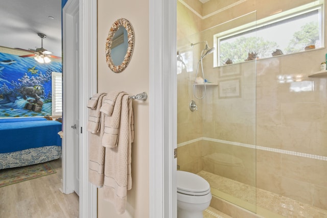 bathroom with tiled shower, toilet, hardwood / wood-style floors, and ceiling fan