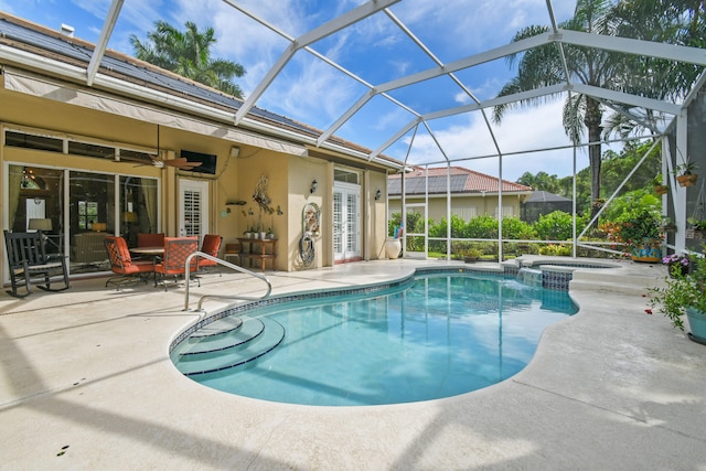 view of pool with glass enclosure, ceiling fan, a patio, and an in ground hot tub