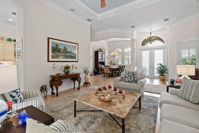 living room with french doors, ornamental molding, and ceiling fan with notable chandelier