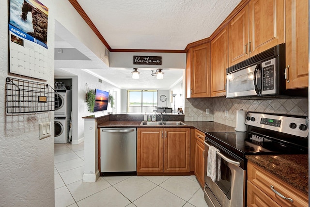 kitchen with stacked washer and dryer, stainless steel appliances, sink, and a textured ceiling