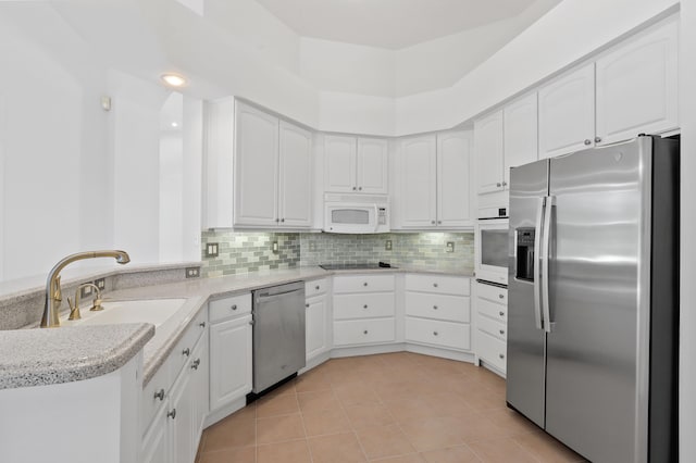 kitchen featuring decorative backsplash, white cabinetry, stainless steel appliances, and light tile patterned floors