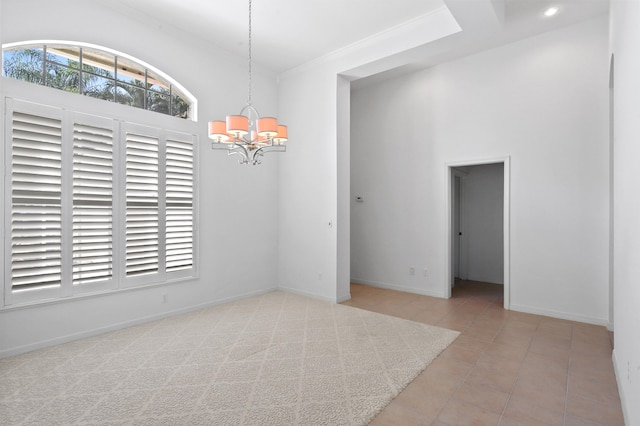 tiled spare room with ornamental molding and a notable chandelier