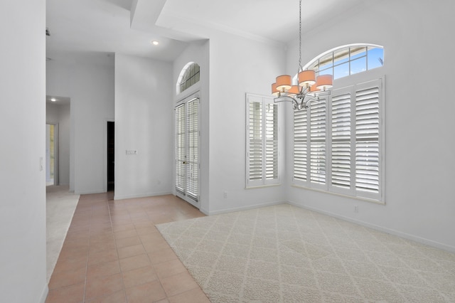 interior space featuring a towering ceiling, ornamental molding, and an inviting chandelier