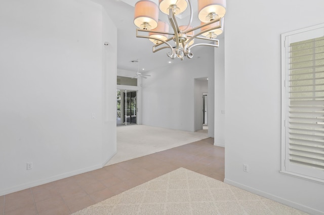 empty room featuring light colored carpet and ceiling fan with notable chandelier