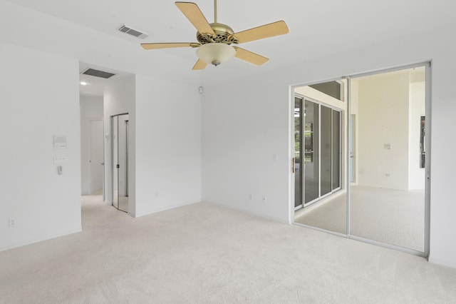 empty room featuring ceiling fan and light carpet