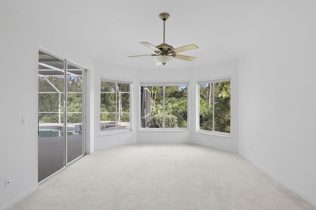 unfurnished sunroom featuring ceiling fan and a healthy amount of sunlight