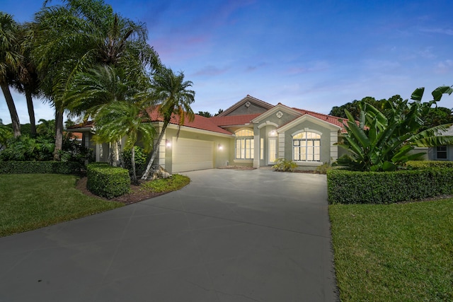 mediterranean / spanish-style house featuring a lawn and a garage