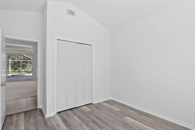 unfurnished bedroom featuring light wood-type flooring, a closet, and lofted ceiling