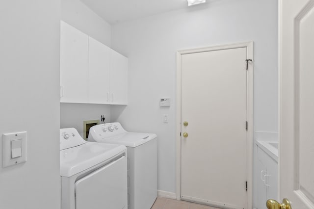 clothes washing area featuring washer and clothes dryer, light tile patterned floors, and cabinets