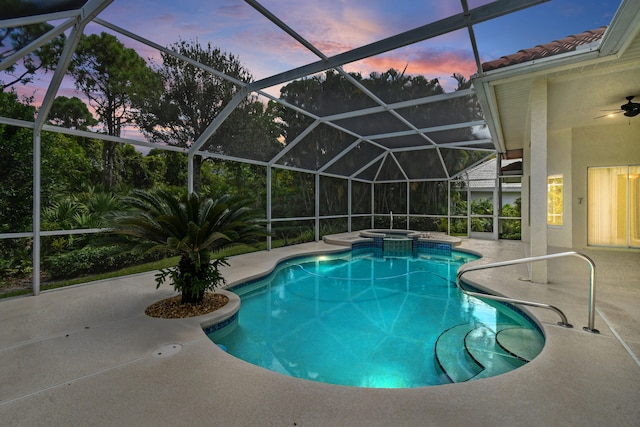 pool at dusk featuring an in ground hot tub, a patio, glass enclosure, and ceiling fan