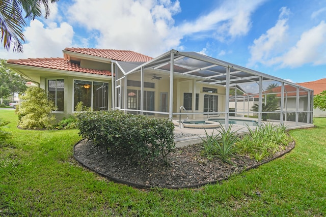 back of house with a lawn, a pool with hot tub, a patio area, and a lanai