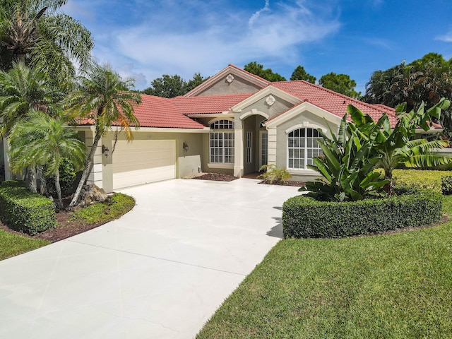 mediterranean / spanish home with a garage and a front lawn