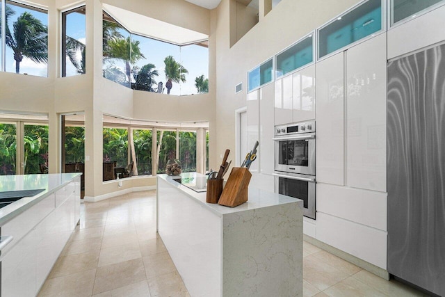 kitchen featuring a wealth of natural light, a high ceiling, light tile patterned floors, and stainless steel appliances