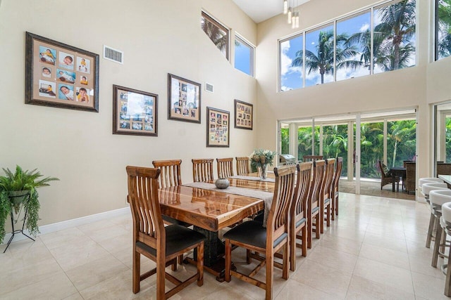 dining area featuring a towering ceiling and light tile patterned flooring