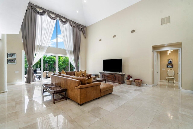 living room with light tile patterned flooring and a towering ceiling