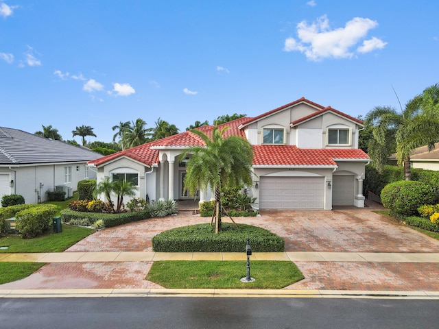 mediterranean / spanish-style home with central air condition unit and a garage