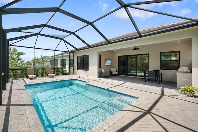 view of swimming pool featuring glass enclosure, ceiling fan, and a patio area