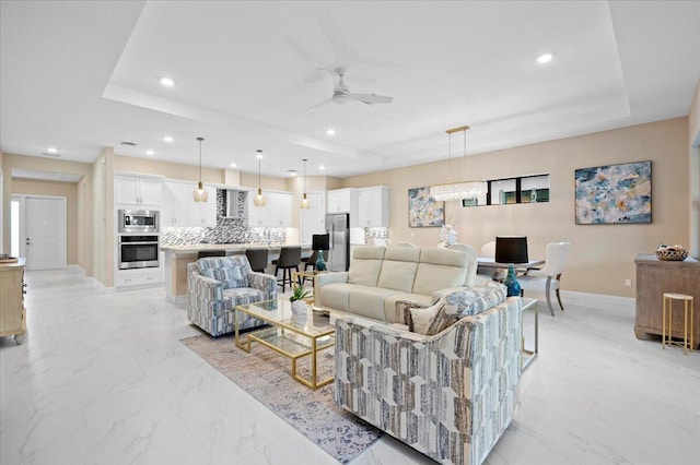 living room featuring ceiling fan and a raised ceiling