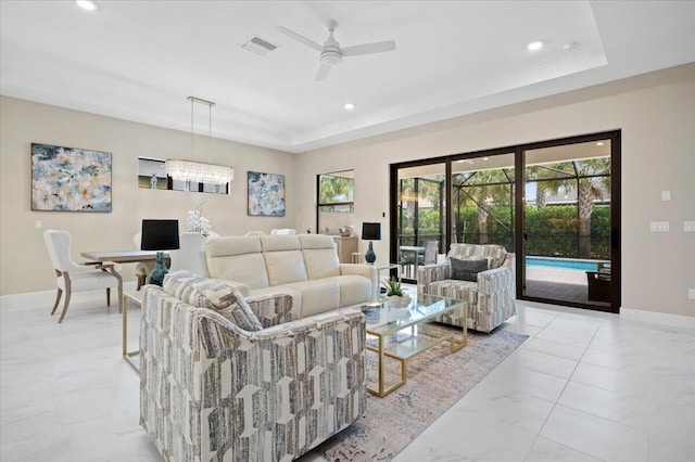 living room featuring ceiling fan and a raised ceiling