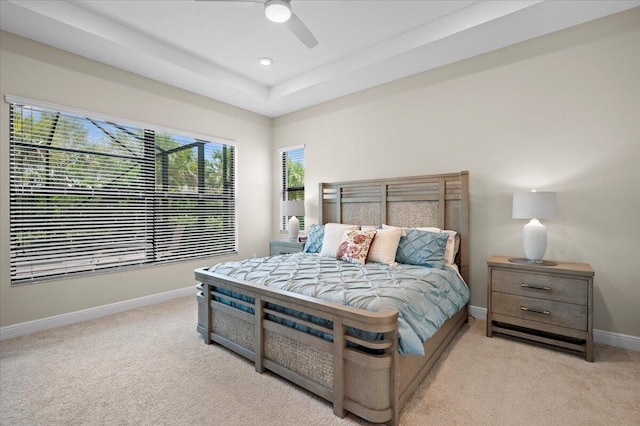 carpeted bedroom with a tray ceiling and ceiling fan