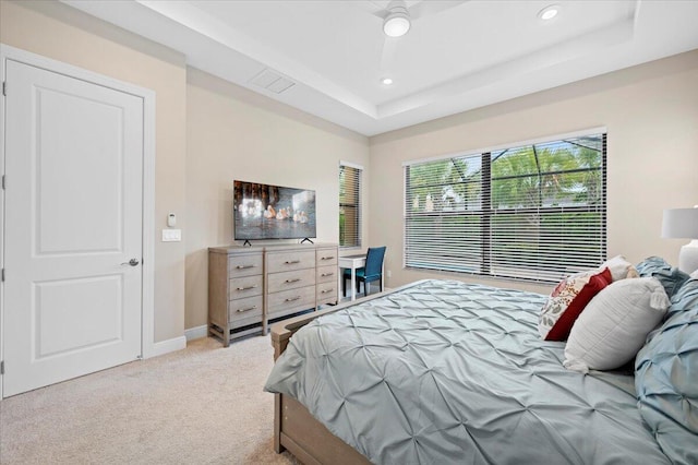 carpeted bedroom featuring ceiling fan and a tray ceiling