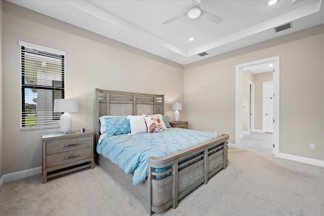 carpeted bedroom with a raised ceiling and ceiling fan