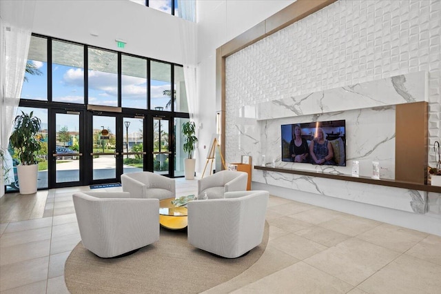 tiled living room with a premium fireplace, a towering ceiling, and french doors