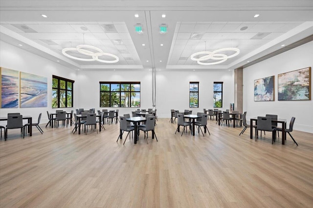 dining space featuring an inviting chandelier, a tray ceiling, and light hardwood / wood-style floors