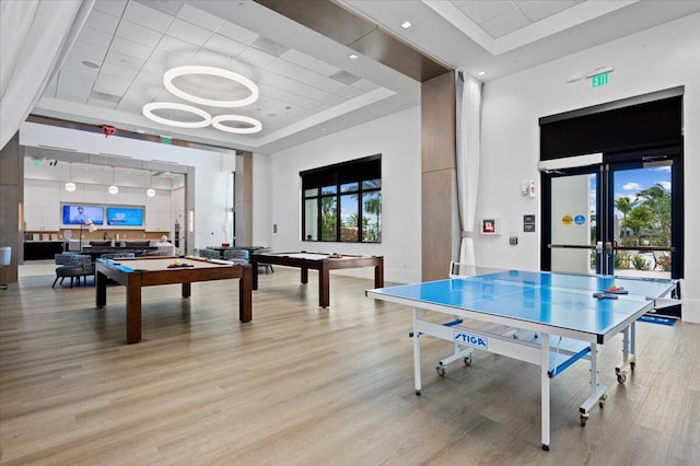 game room featuring a tray ceiling, light hardwood / wood-style floors, and pool table