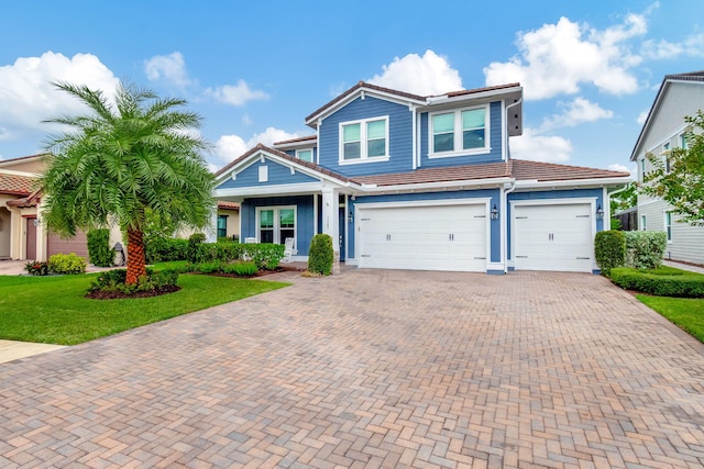 view of front of property featuring a garage, a front yard, decorative driveway, and a tiled roof