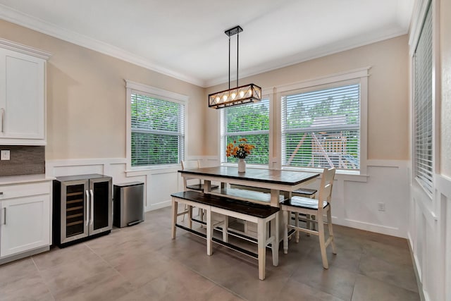 dining space with crown molding, wine cooler, wainscoting, and a healthy amount of sunlight