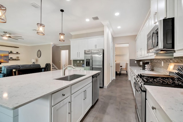 kitchen with appliances with stainless steel finishes, white cabinets, a kitchen island with sink, a sink, and light stone countertops