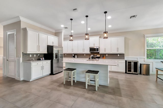 kitchen with a center island with sink, white cabinetry, appliances with stainless steel finishes, and pendant lighting