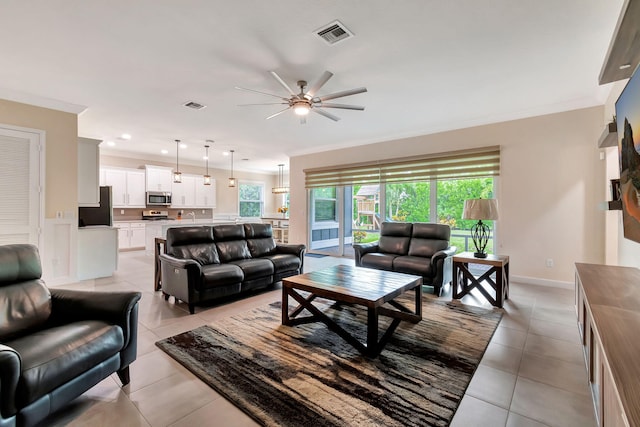 tiled living room with ceiling fan and ornamental molding