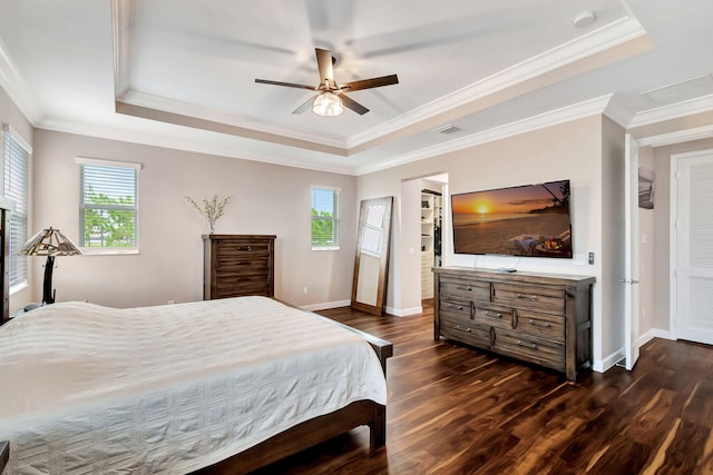 bedroom featuring multiple windows, dark hardwood / wood-style flooring, ceiling fan, and a tray ceiling