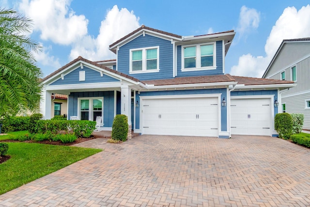 view of front of house featuring a garage, a tiled roof, and decorative driveway