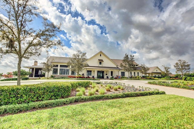 view of front facade featuring a standing seam roof, a chimney, metal roof, and a front yard