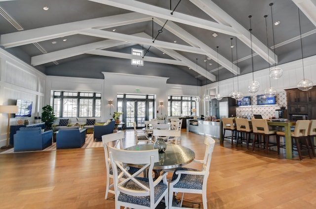 dining space featuring beam ceiling, high vaulted ceiling, and light hardwood / wood-style floors