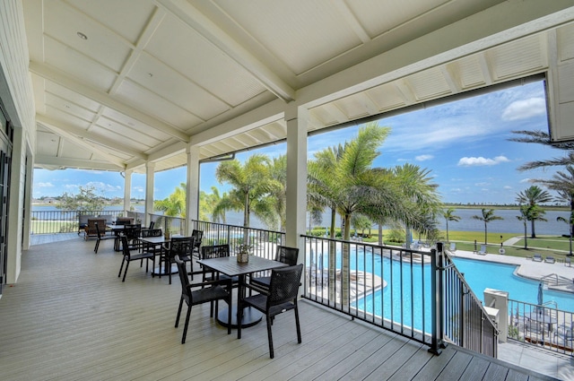 wooden terrace featuring a patio, a water view, and a community pool