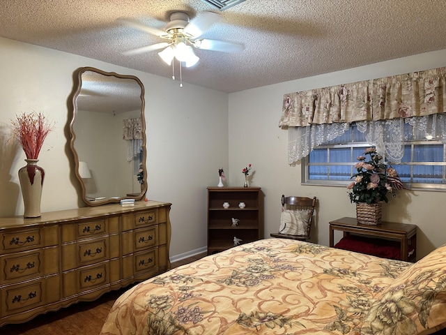 bedroom with ceiling fan, dark hardwood / wood-style flooring, and a textured ceiling