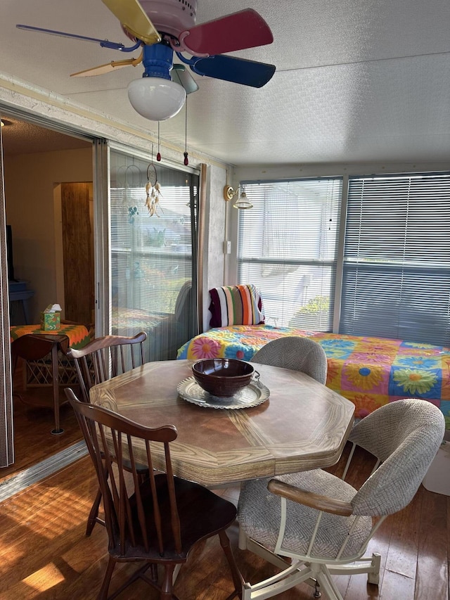 dining area with ceiling fan with notable chandelier, wood-type flooring, and a textured ceiling