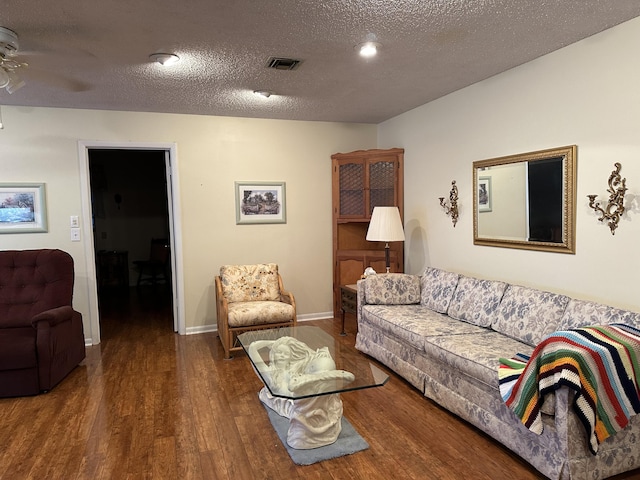 living room featuring hardwood / wood-style floors, ceiling fan, and a textured ceiling