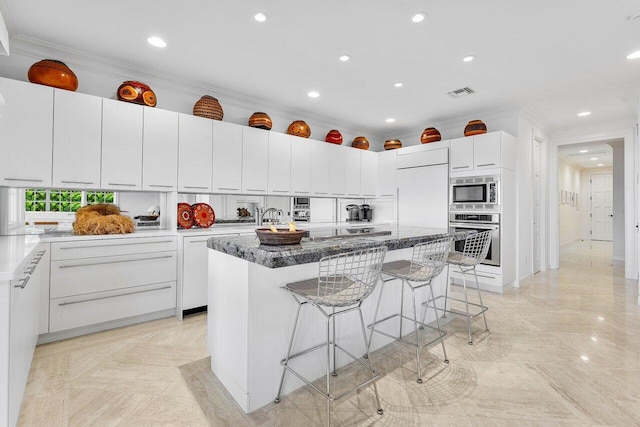 kitchen featuring built in appliances, a breakfast bar area, visible vents, and crown molding