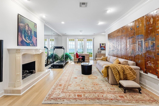 living room featuring light wood-style floors, a fireplace, visible vents, and crown molding