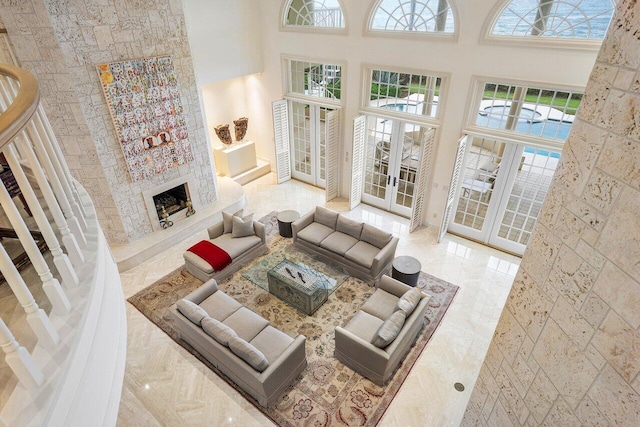 living area featuring a high ceiling, a fireplace, and french doors